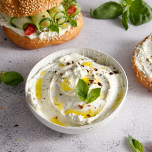 Cheese curd spread for breakfast with herbs, sun-dried tomatoes and olive oil close-up