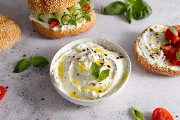 Cheese curd spread for breakfast with herbs, sun-dried tomatoes and olive oil close-up