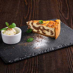 Layered cheesecake with ice cream served on slate plate