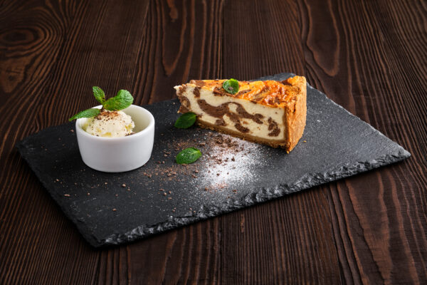 Layered cheesecake with ice cream served on slate plate