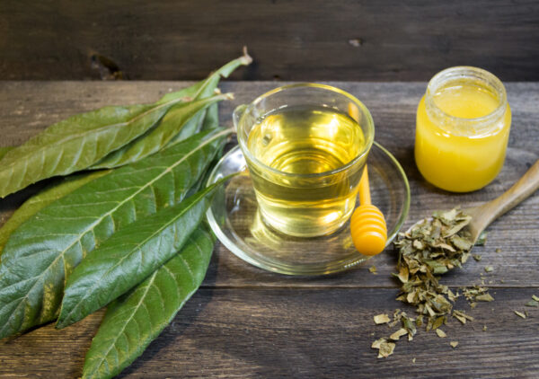 medicinal infusion of loquat leaves with honey, on rustic wooden background