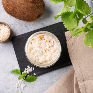 Rice porridge with coconut milk and mango slices in a jar on a light background.